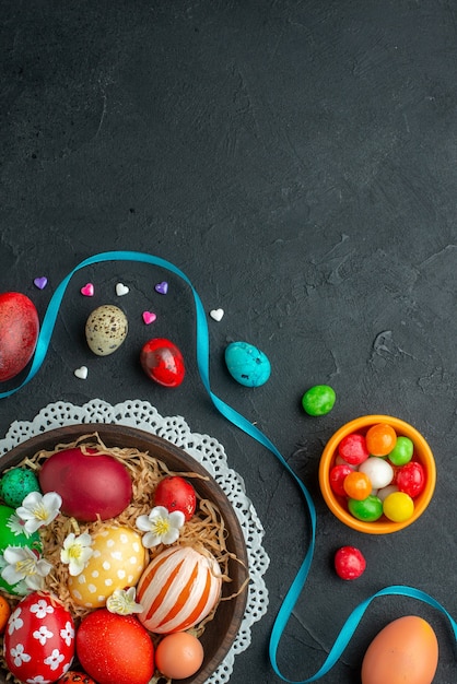 Vista superior de huevos de pascua de colores sobre una superficie oscura