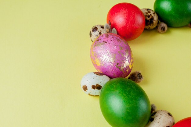 Foto vista superior huevos pintados marco de pascua en forma de círculo sobre un fondo amarillo. copia espacio