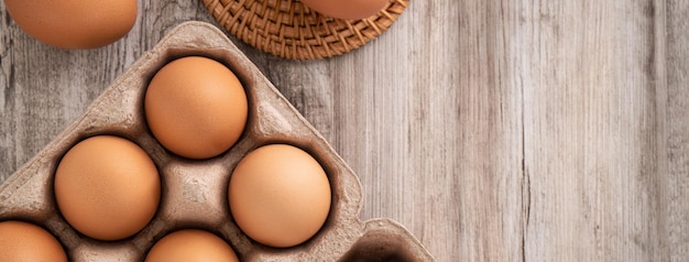 Vista superior de huevos de pollo marrones frescos en un cartón de huevos de papel kraft sobre fondo de mesa de madera