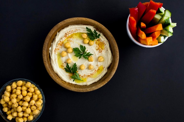 Vista superior de hummus en el tazón y vegetales en el fondo negro Espacio de copia de primer plano