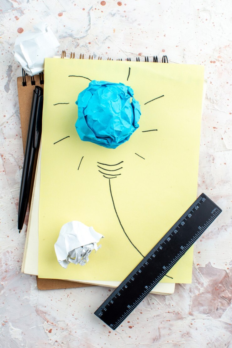 Foto vista superior idea bombilla concepto sobre papel regla negra y bolígrafo papeles arrugados sobre la mesa