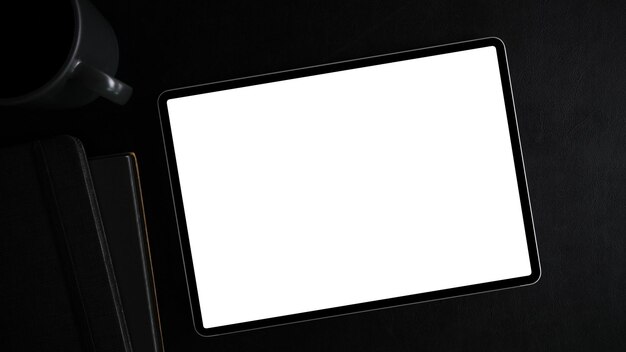 Vista superior, imagem plana leiga de uma maquete de tela branca de computador tablet no moderno espaço de trabalho preto.