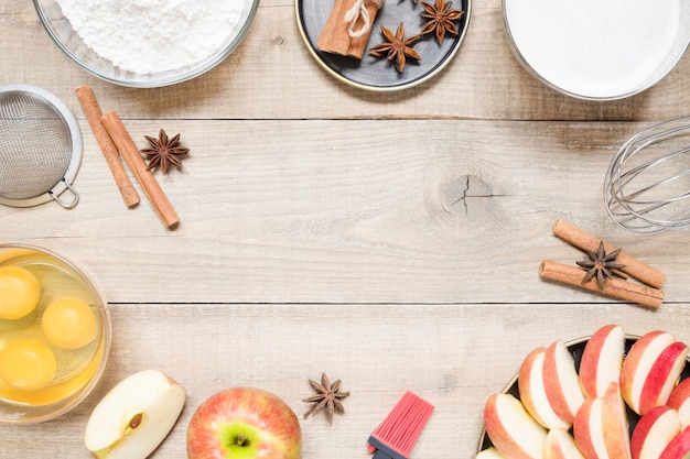 Vista superior de ingredientes crudos para cocinar tarta de manzana sobre fondo de madera con espacio de copia