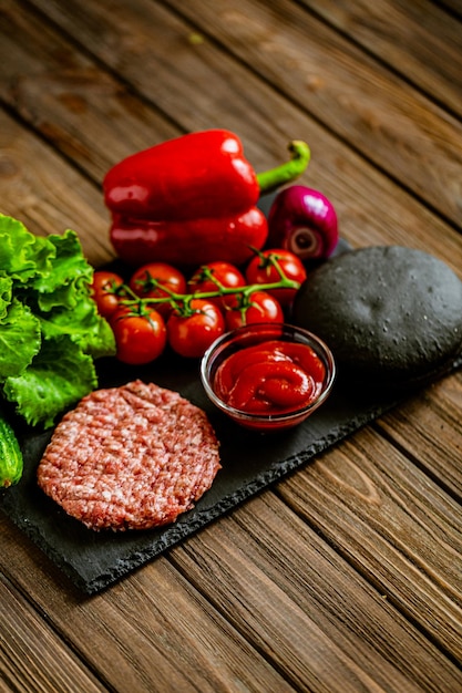 Vista superior de los ingredientes para la hamburguesa negra de ternera en un concepto de comida deliciosa de tablero de piedra negra