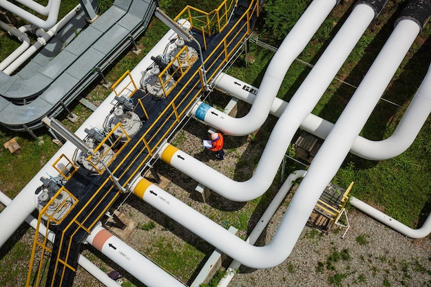 Vista superior de la inspección del trabajador masculino en la válvula del registro de control visual de la tubería de petróleo y gas