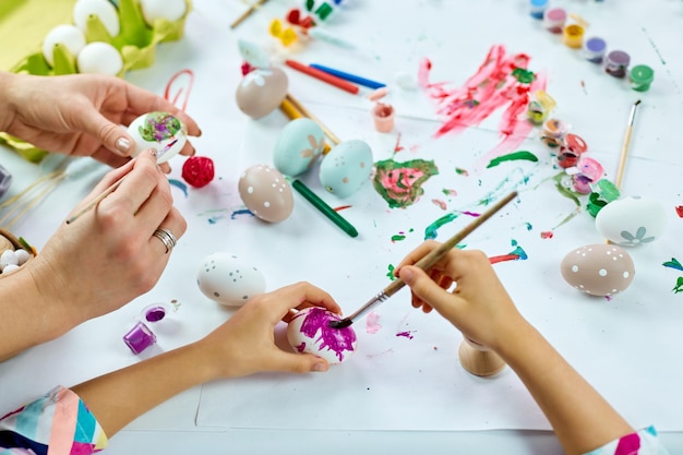 Vista superior irreconhecível mãe e filha no feriado de páscoa colorindo ovos de páscoa