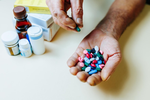 Foto vista superior irreconhecível na mão um punhado de medicamentos dos quais a outra mão toma um comprimido