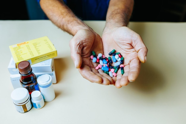 Vista superior irreconhecível na mão um punhado de medicamentos dos quais a outra mão toma um comprimido