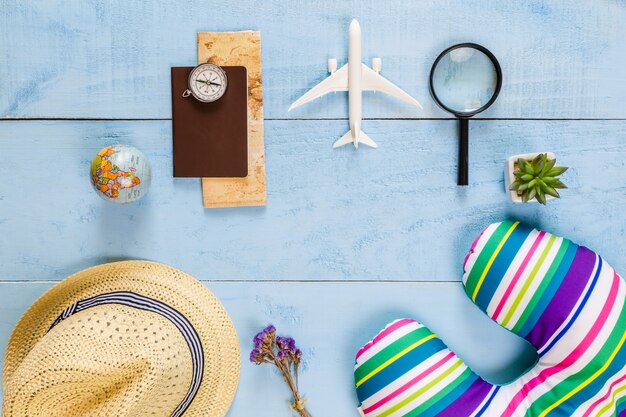 Vista superior itens essenciais de viagem. mapa, passaporte, avião, fundo azul de madeira.