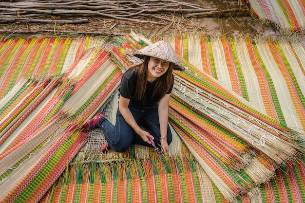 Vista superior del joven artesano vietnamita haciendo las tradicionales esteras de Vietnam con felicidad