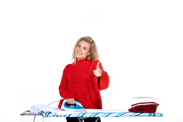 Vista superior de la joven y sonriente mujer hermosa planchando ropa haciendo gesto ok sobre fondo blanco.