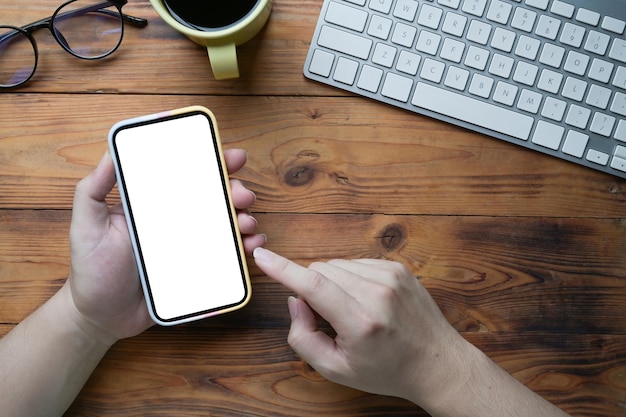 Vista superior joven usando un teléfono inteligente en un escritorio de madera