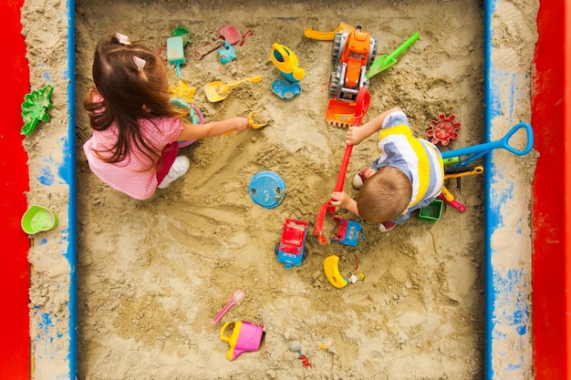 Vista superior de juegos para niños en el arenero. Niño y niña cavando en la arena. Tiempo en familia juntos