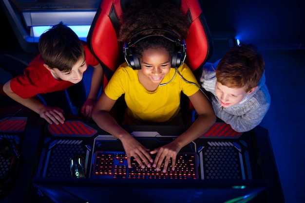 Vista superior de una jugadora afroamericana jugando videojuegos con amigos en la computadora en la sala de juegos