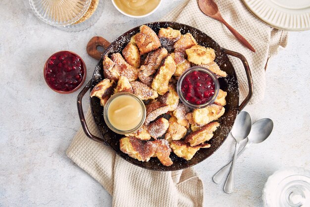 Vista superior de kaiserschmarrn con panqueques rotos, mermelada de arándanos y puré de manzana en una mesa