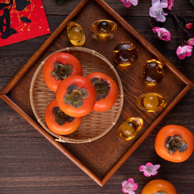 Vista superior de kaki de caquis dulces frescos con hojas sobre fondo de mesa de madera para el concepto de diseño de frutas de año nuevo lunar chino, la palabra significa bendición viene