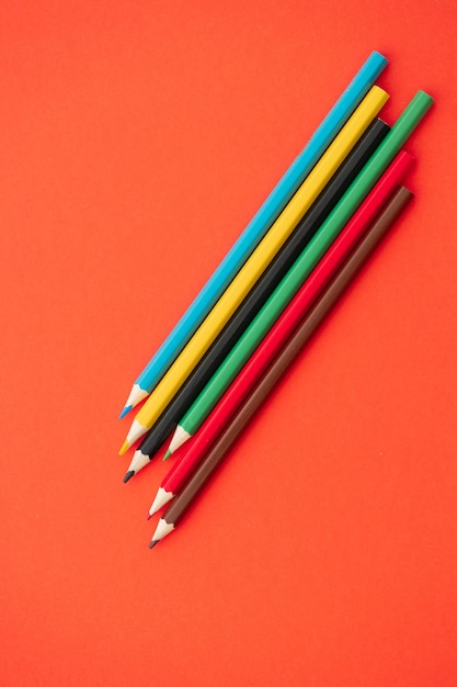 Foto vista superior de lápices de colores sobre fondo rojo.