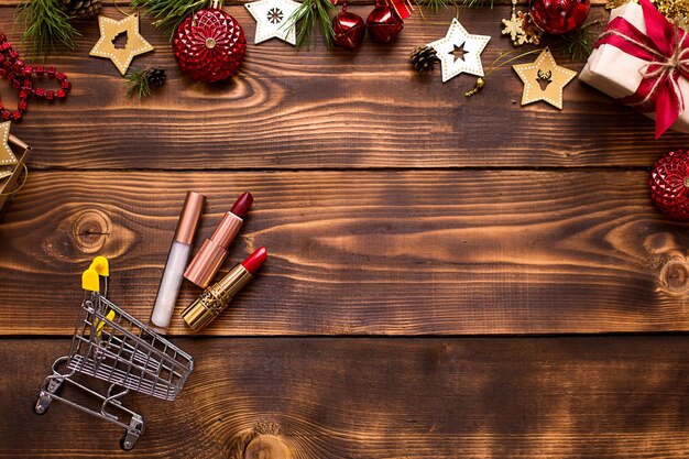 Vista superior de lápices labiales con carrito de compras y adornos navideños