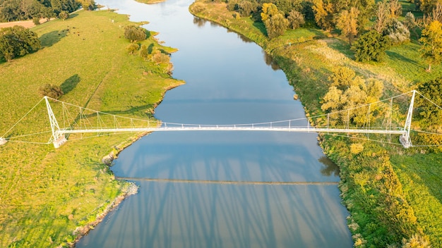 Vista superior de un largo puente peatonal sobre el río azul Odra, Polonia. Puente colgante moderno