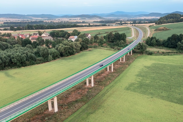 Vista superior de un largo puente que pasa por campos verdes