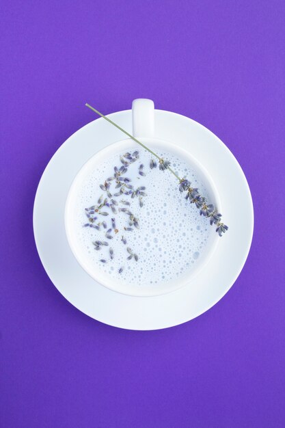 Vista superior de la leche de luna de lavanda en la taza blanca sobre la superficie violeta