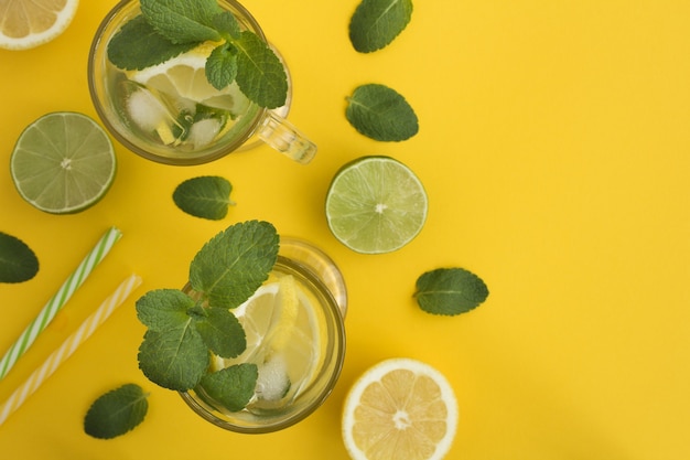 Foto vista superior de limonada fría con limón y menta en la superficie amarilla