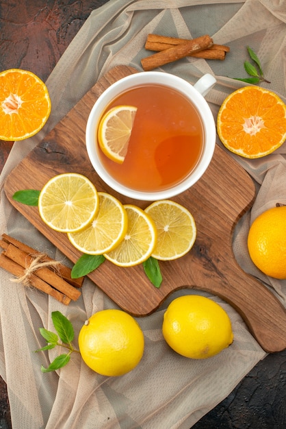 Vista superior de limones amarillos frescos con una taza de té sobre fondo oscuro fruta de color cítrico foto de árbol maduro té