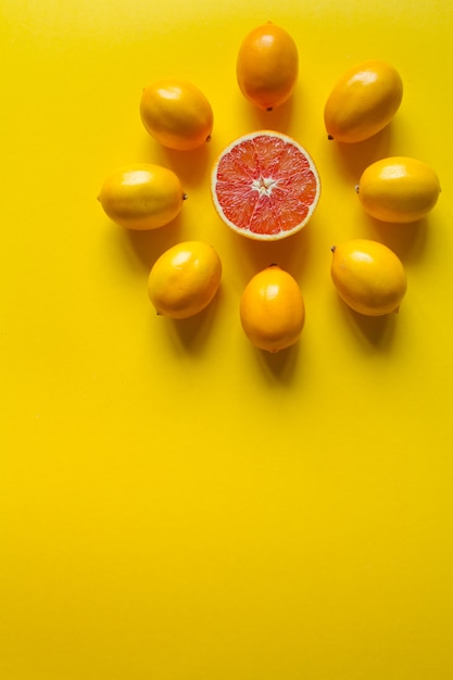 Vista superior de limones maduros enteros y en rodajas y pomelo en forma de esfera sobre una superficie amarilla, concepto de salud y vitaminas