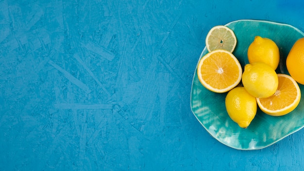 Foto vista superior de limones en placa con fondo azul