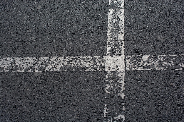 Vista superior de líneas blancas de carretera en mal estado sobre el asfalto