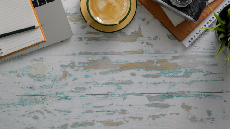 Foto vista superior del lugar de trabajo rústico con computadora portátil, cámara, suministros de oficina, taza de café y espacio de copia