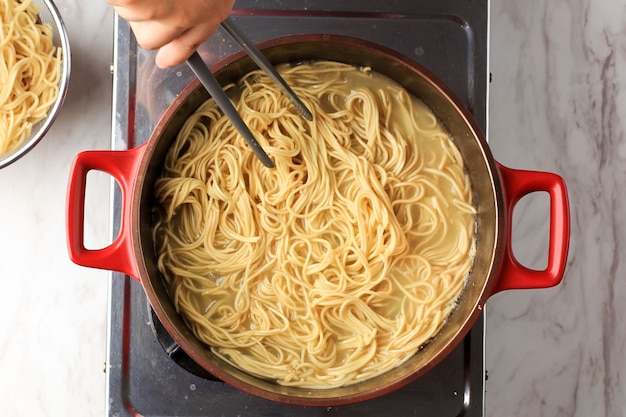 Vista superior Macarrão instantâneo coreano fervente ou macarrão com espaguete na frigideira vermelha, atividade culinária caseira