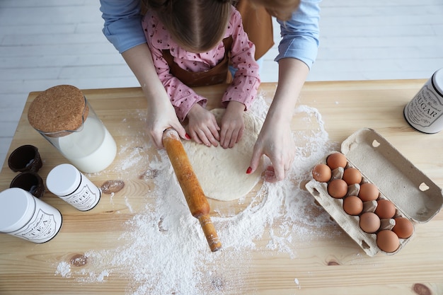 Vista superior de madre e hija en la cocina cocinando con harina y huevos