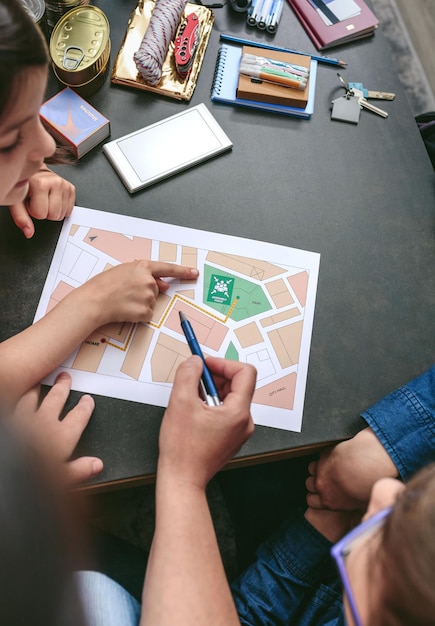 Foto vista superior de una madre explicando a los niños el mapa del punto de reunión mientras prepara mochilas de emergencia