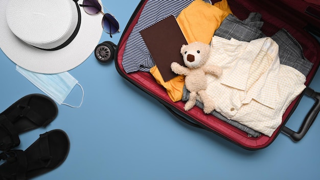 Vista superior mala aberta com roupas casuais e passaportes sobre fundo azul Conceito de bagagem de voo de turismo de viagens de férias