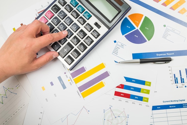 Foto vista superior de una mano escribiendo en una calculadora en el fondo de gráficos hojas de cálculo gráfico de desarrollo financiero cuentas bancarias estadísticas economía análisis de datos análisis de inversión bolsa de valores