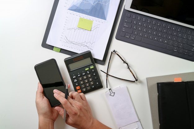 Vista superior de la mano del hombre de negocios que trabaja con las finanzas sobre el costo y la calculadora y el latop con el teléfono móvil en con el escritorio en la oficina moderna