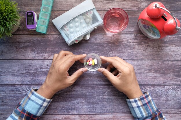 Vista superior de la mano del hombre tomando la medicina en la mesa