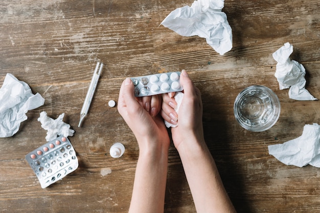 Foto vista superior de la mano de la mujer con blíster sobre fondo de madera