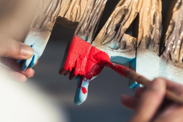 Vista superior de la mano de una persona pintando letras de poliestireno en rojo