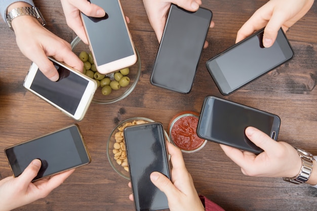 Vista superior manos círculo usando el teléfono en la cafetería