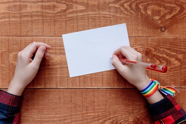 Foto vista superior de las manos escribiendo una nota sobre fondo de madera