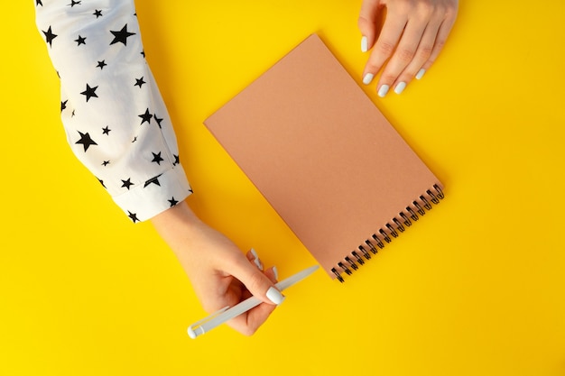 Vista superior de manos femeninas escribiendo en el cuaderno