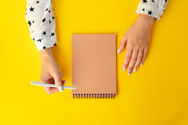 Vista superior de manos femeninas escribiendo en el cuaderno