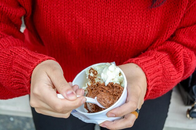 vista superior de manos femeninas tomando una porción de helado con una cuchara pequeña