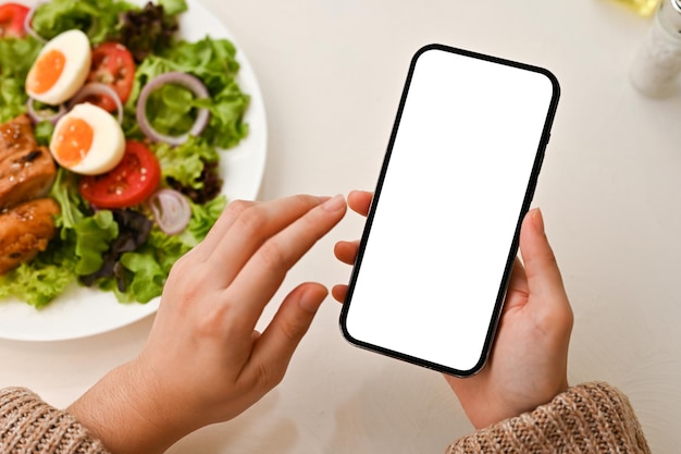 Vista superior Manos femeninas usando un teléfono inteligente sobre su mesa de comedor