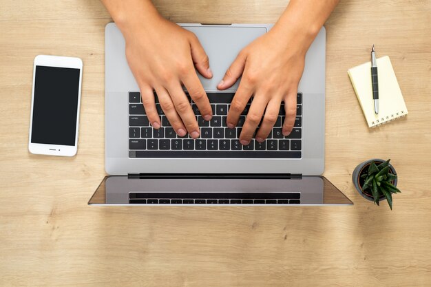 Foto vista superior de manos humanas trabajando en una computadora portátil moderna, navegando en línea, escribiendo un texto, navegando en internet