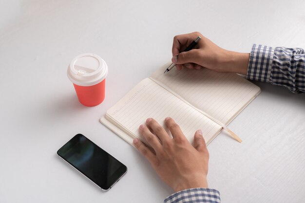 Foto vista superior de las manos con lápiz tomando notas en su lugar de trabajo