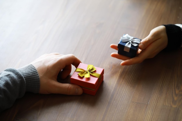 Vista superior de manos masculinas y femeninas sosteniendo caja de regalo con cinta sobre fondo de madera Presente para cumpleaños día de San Valentín Navidad Año Nuevo Felicitaciones espacio de copia de fondo