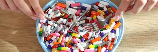 Vista superior de las manos del médico sosteniendo pastillas en un cuenco en forma de corazón Farmacista con cápsulas de colores Concepto de medicina y tratamiento